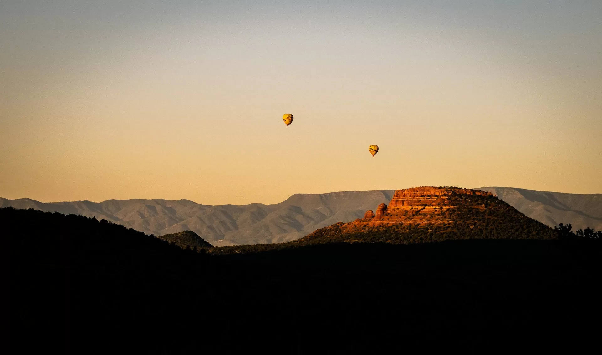 De rotsen en bergen in Sedona met twee luchtballonnen in de lucht
