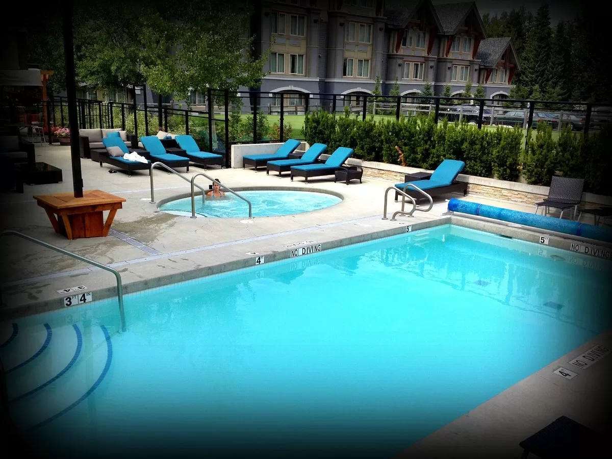 Buitenzwembad met jacuzzi en ligbedden in het Hotel Aava Whistler