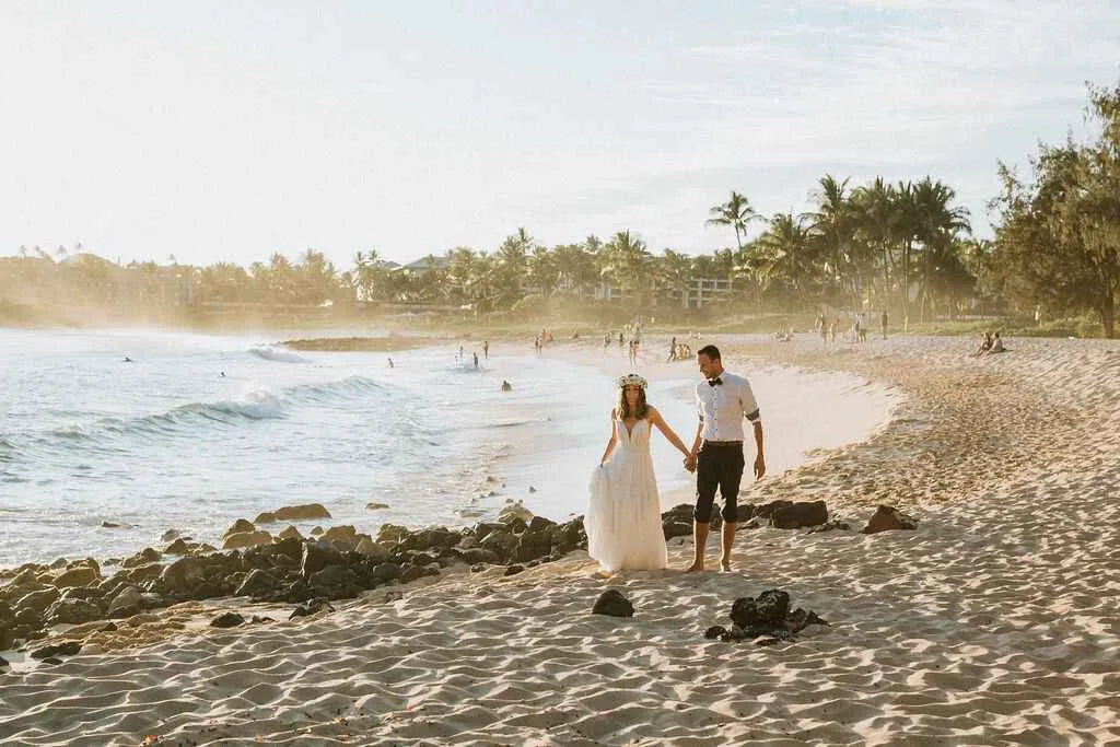 Een pasgetrouwd stel lopend op het strand van Hawaii