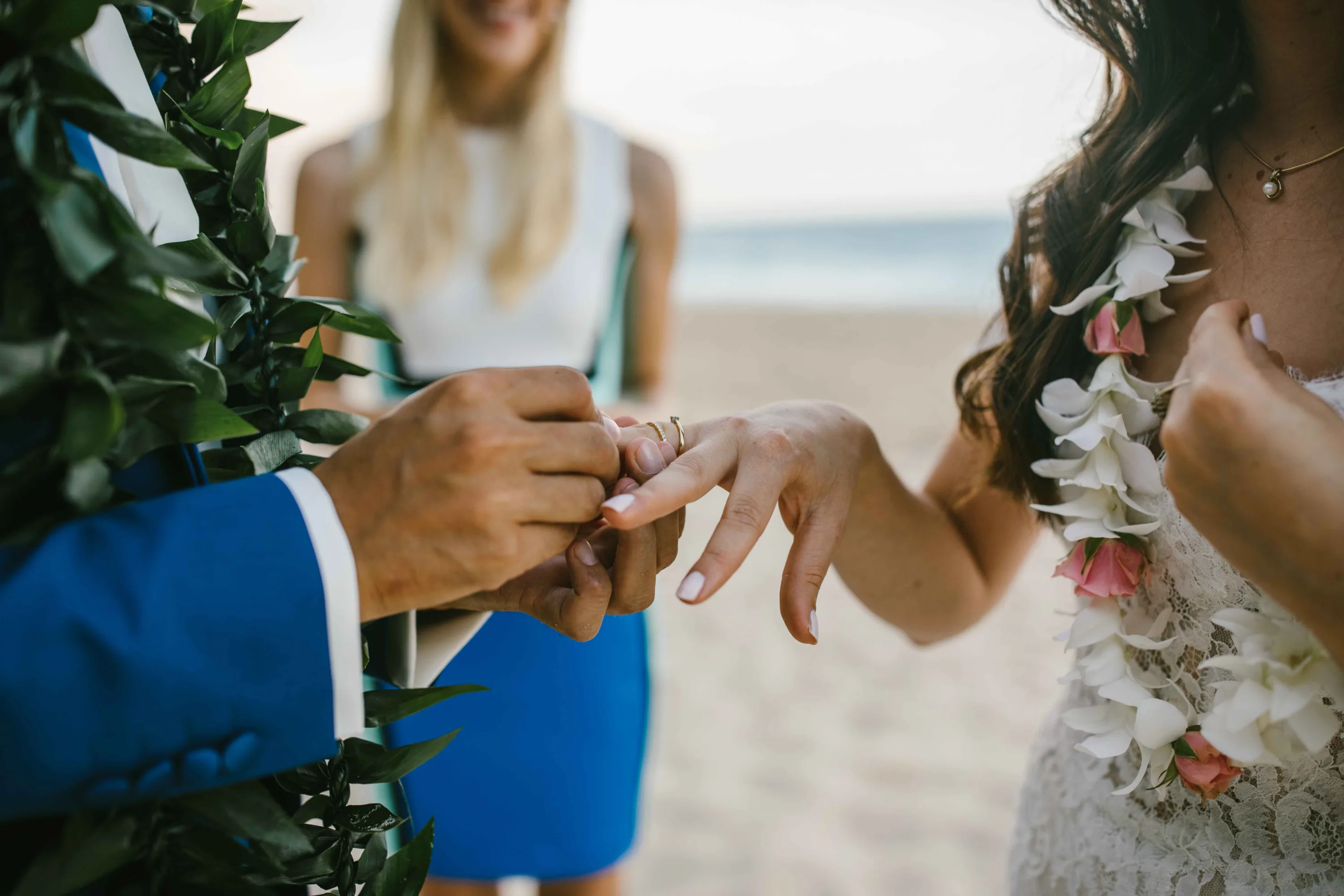 Bruidegom doet de trouwring om bij zijn bruid op een strand op Hawaii