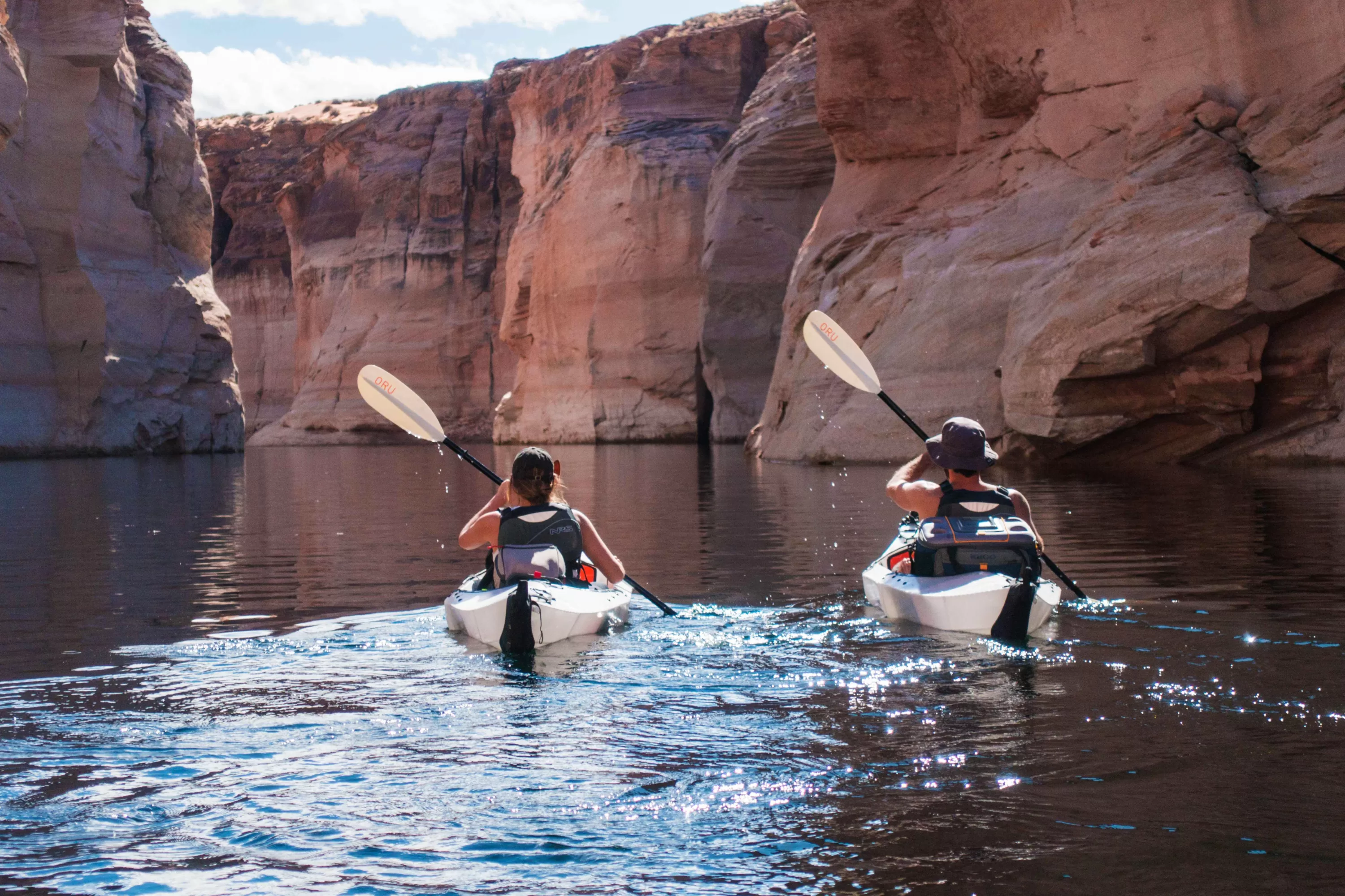 Twee personen kajakken op Lake Powell richting de red rocks