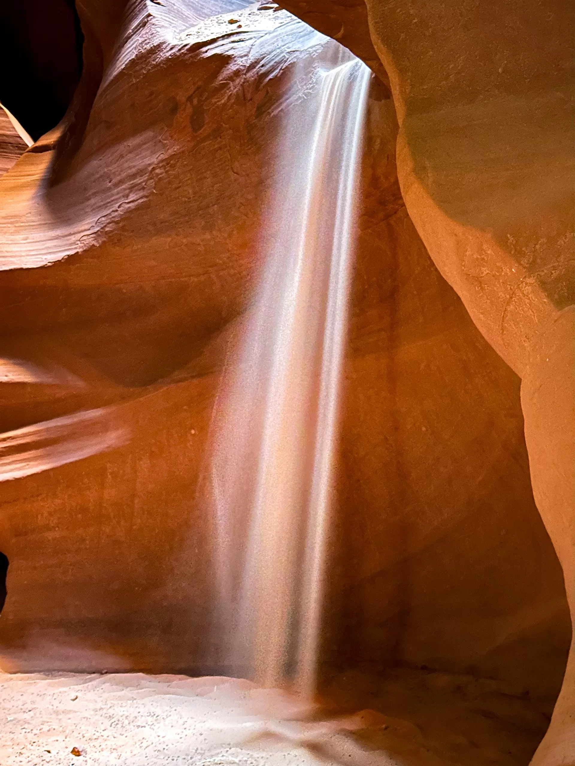 Zand stroomt als een waterval naar beneden in Antelope Canyon, tussen rode wanden in Arizona.