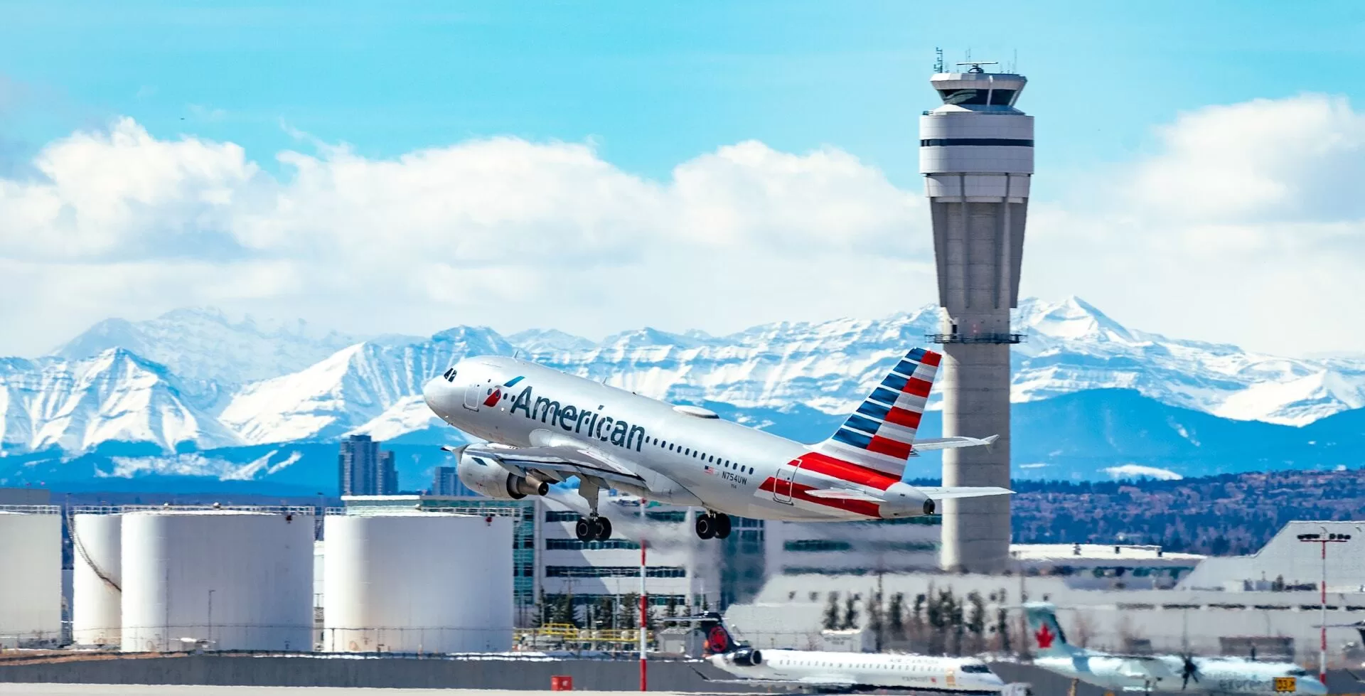 American Airlines-vliegtuig stijgt op met bergen en het vliegveld op de achtergrond