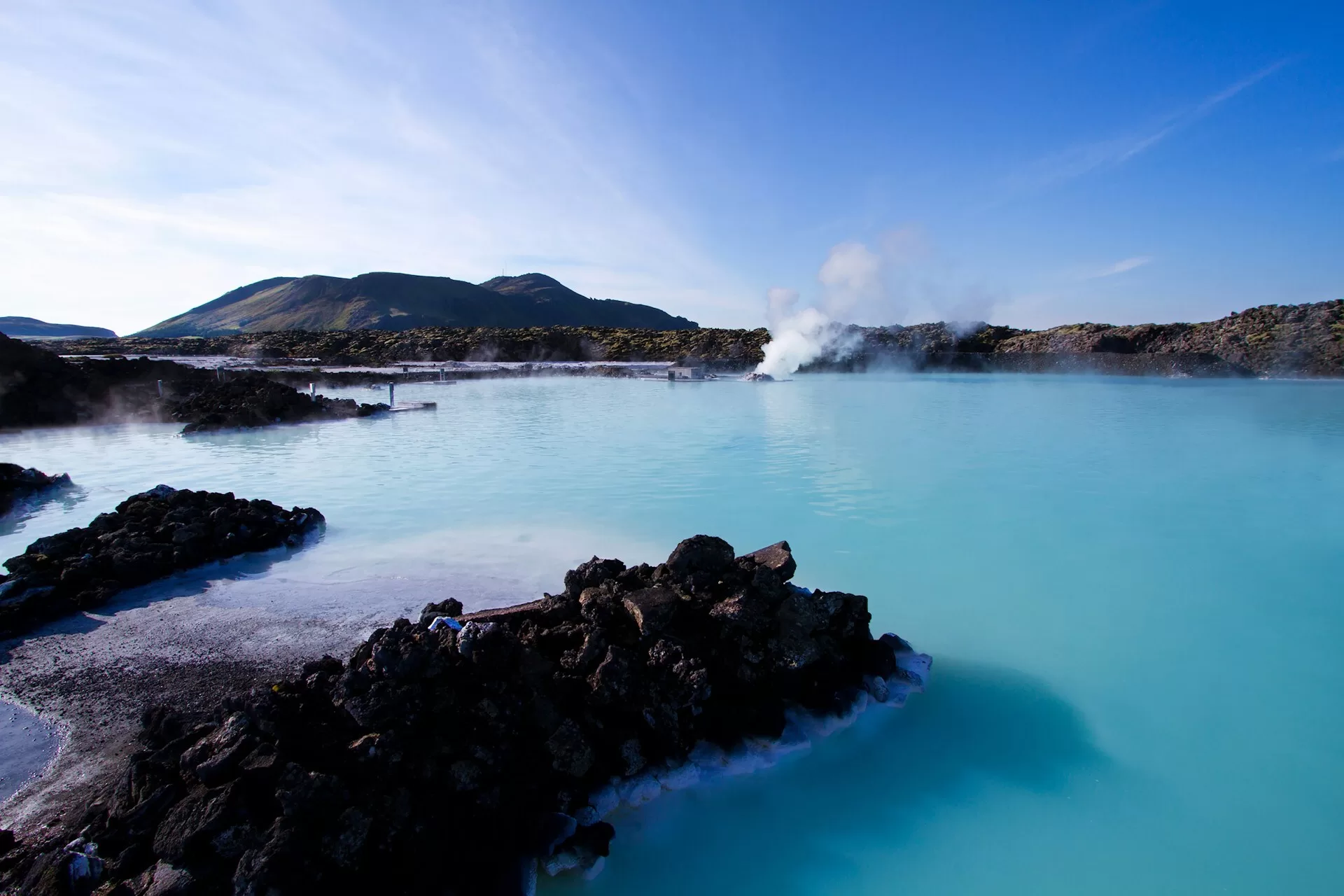 De lichtblauwe Blue Lagoon in Reykjavík met spuitende geiser op de achtergrond