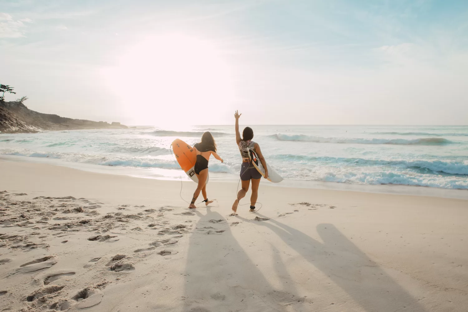 Twee jonge vrouwen met surfboard op het strand van Californië
